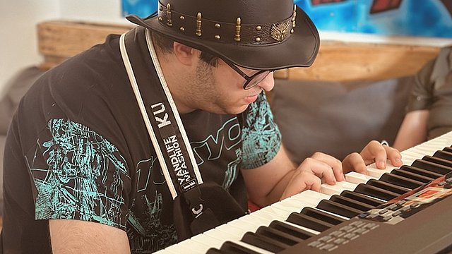 Ein junger Mann sitzt an einem E-Piano und spielt ein Lied