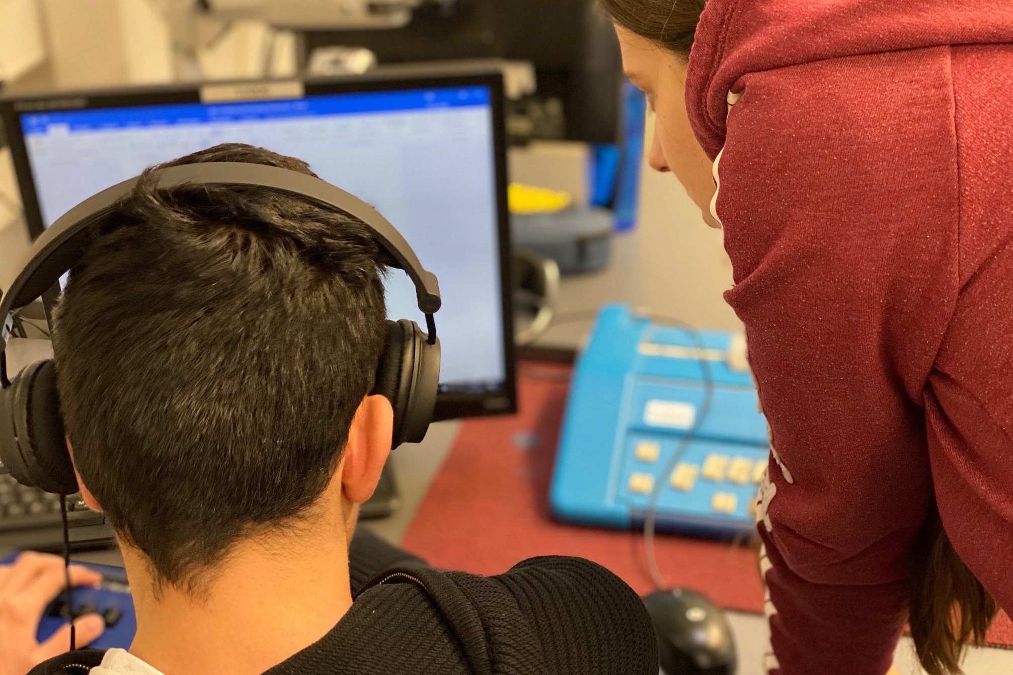 Eine Schülerin erklärt einem Schüler eine Aufgabe am Computer