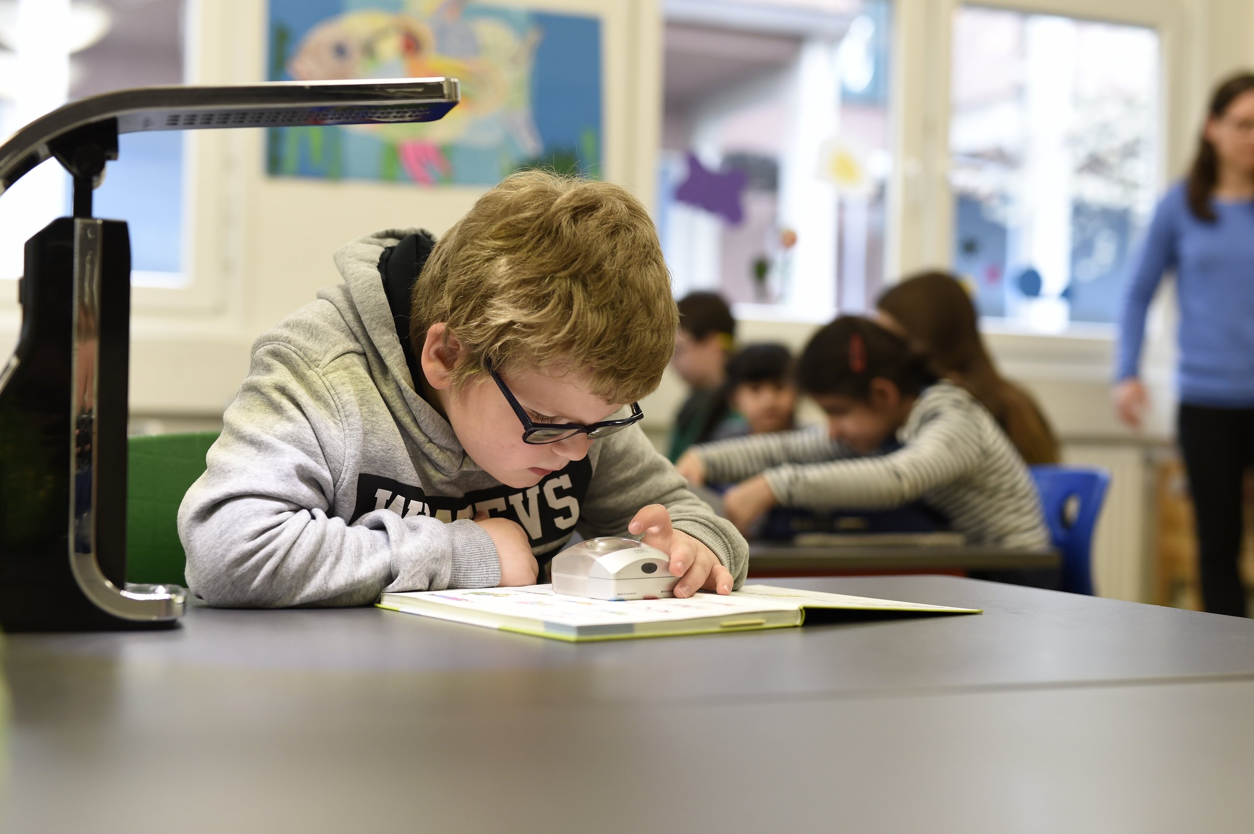 Ein Schüler liest mithilfe einer Leselupe