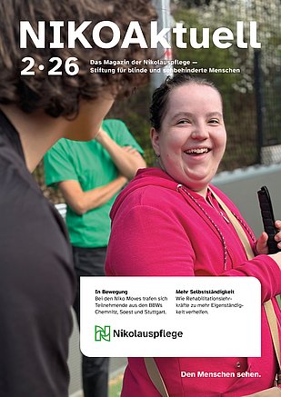 Das Titelbild des Magazins NIKOAktuell 2/2026. Eine junge Frau mit rotem Oberteil lacht in die Kamera. Sie ist draußen und hält einen Langstock in der Hand.