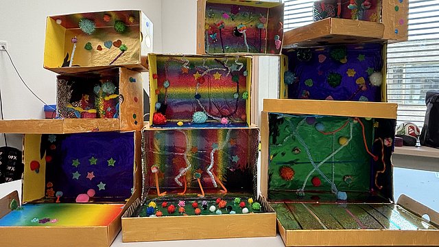 Viele bunt gestaltete Pappkartons stehen aufeinander auf einem Tisch im Klassenzimmer