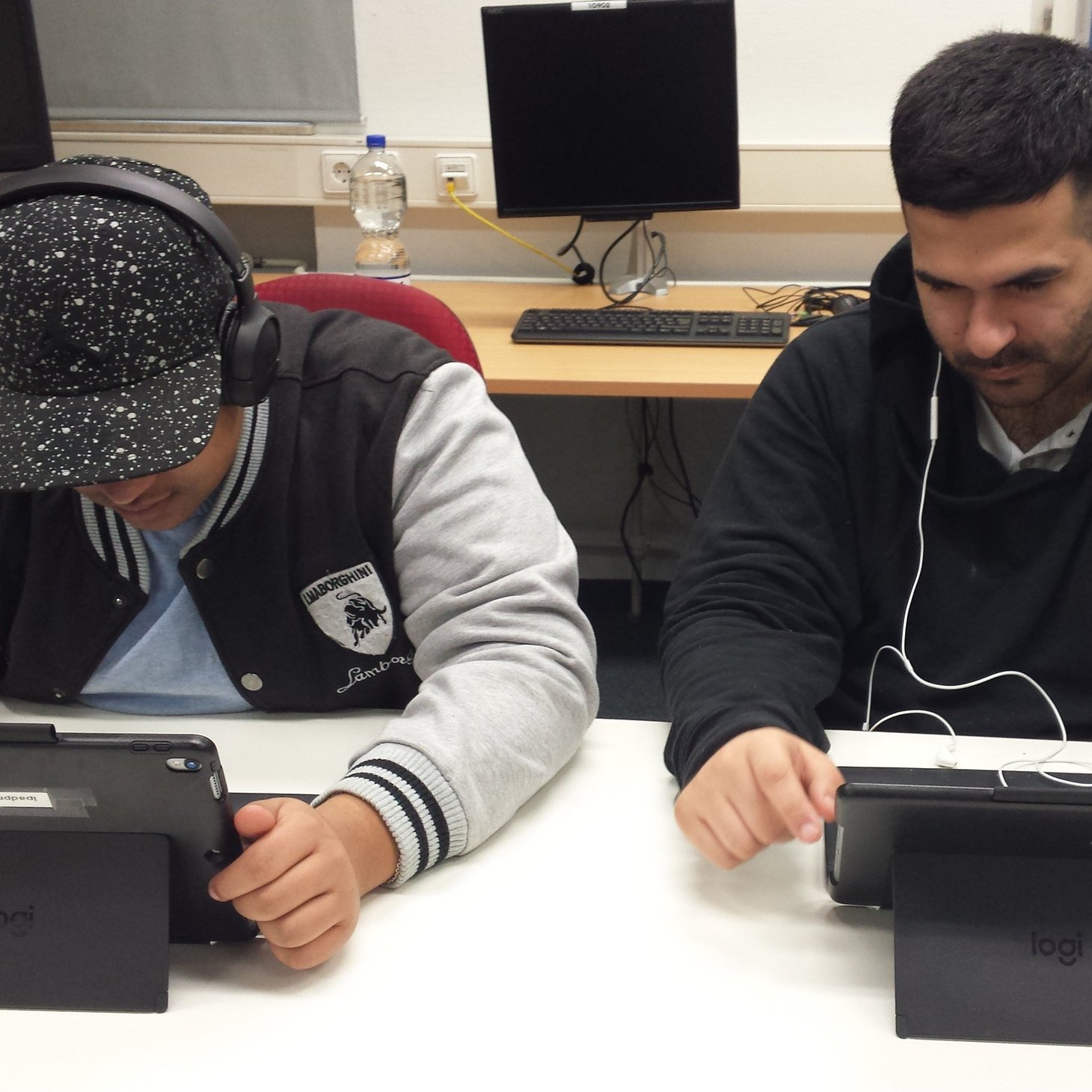Zwei Schüler sitzen mit Kopfhörern vor einem Tablet