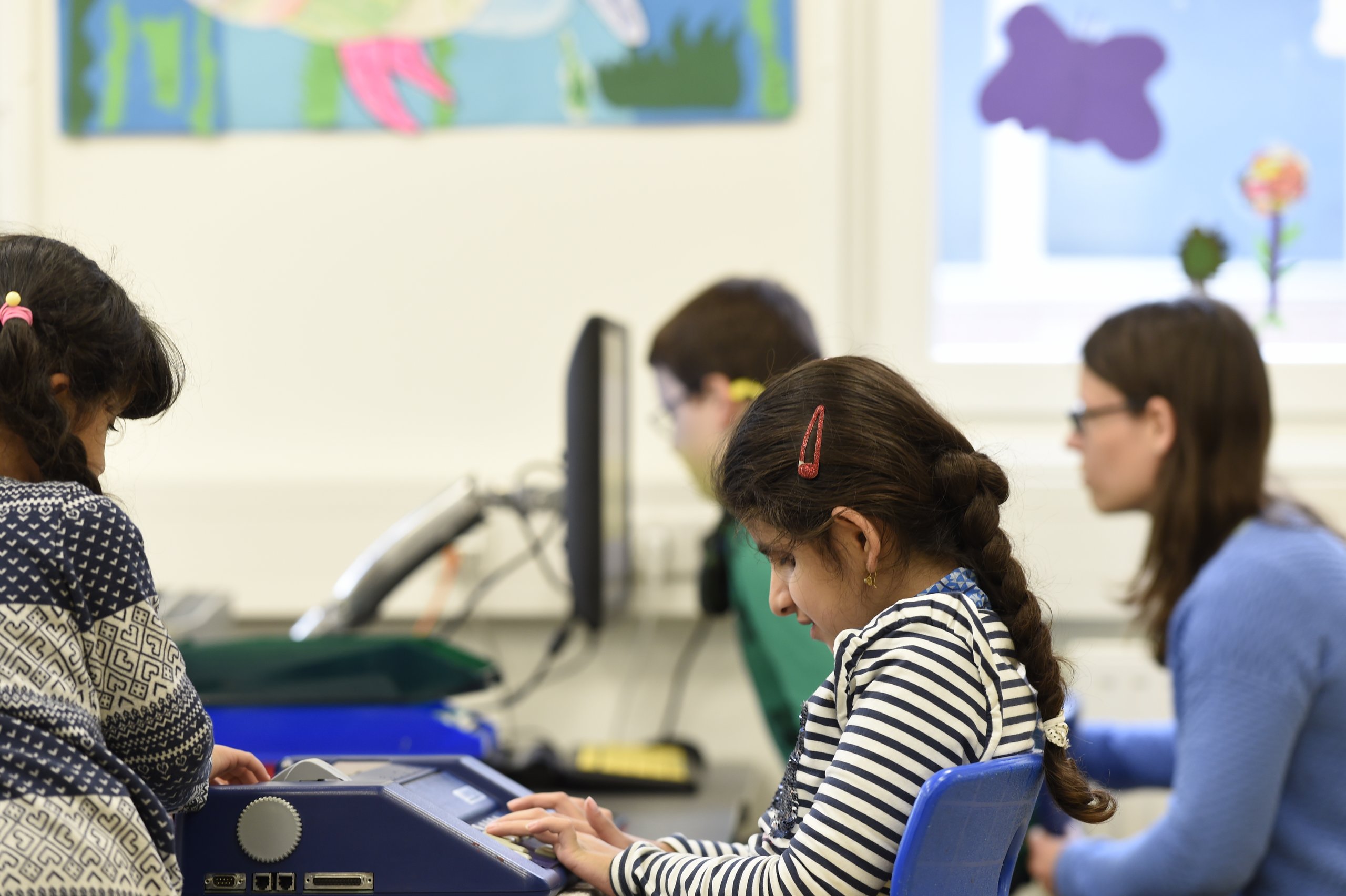 Mehrere Schülerinnen und Schüler bearbeiten mit Hilfsmitteln Schulaufgaben