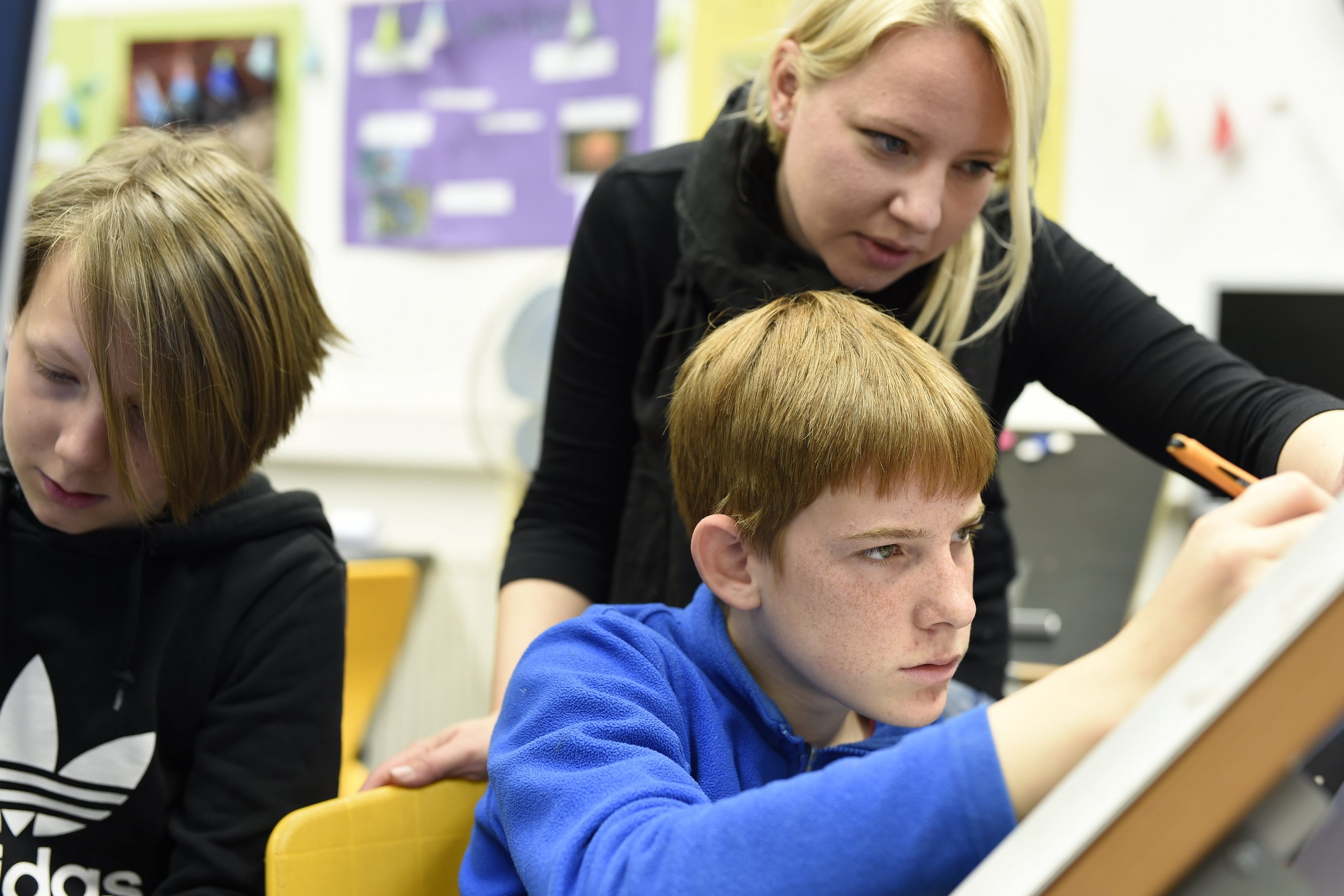 Eine Lehrerin hilft einem Schüler beim Lesen