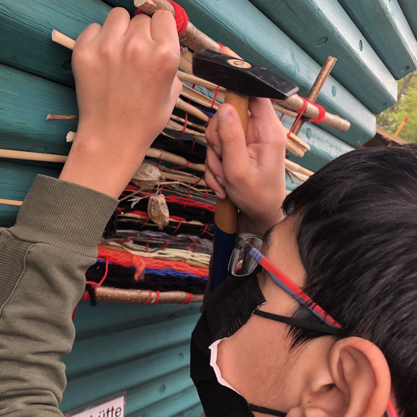 Schüler schlägt Nagel in eine Holzwand