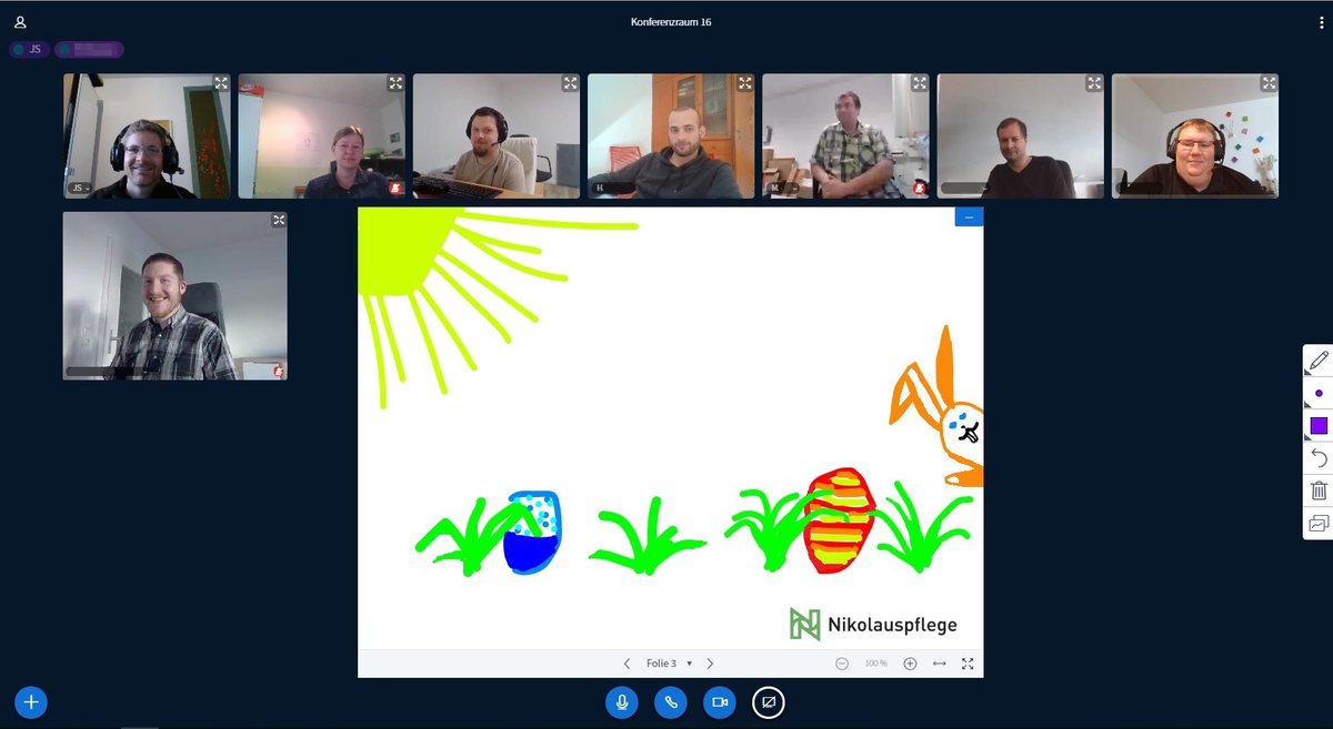 Ein Bildschirm zeigt eine Videokonferenz mit acht Teilnehmenden. In der Mitte ein gemaltes Osterbild. 