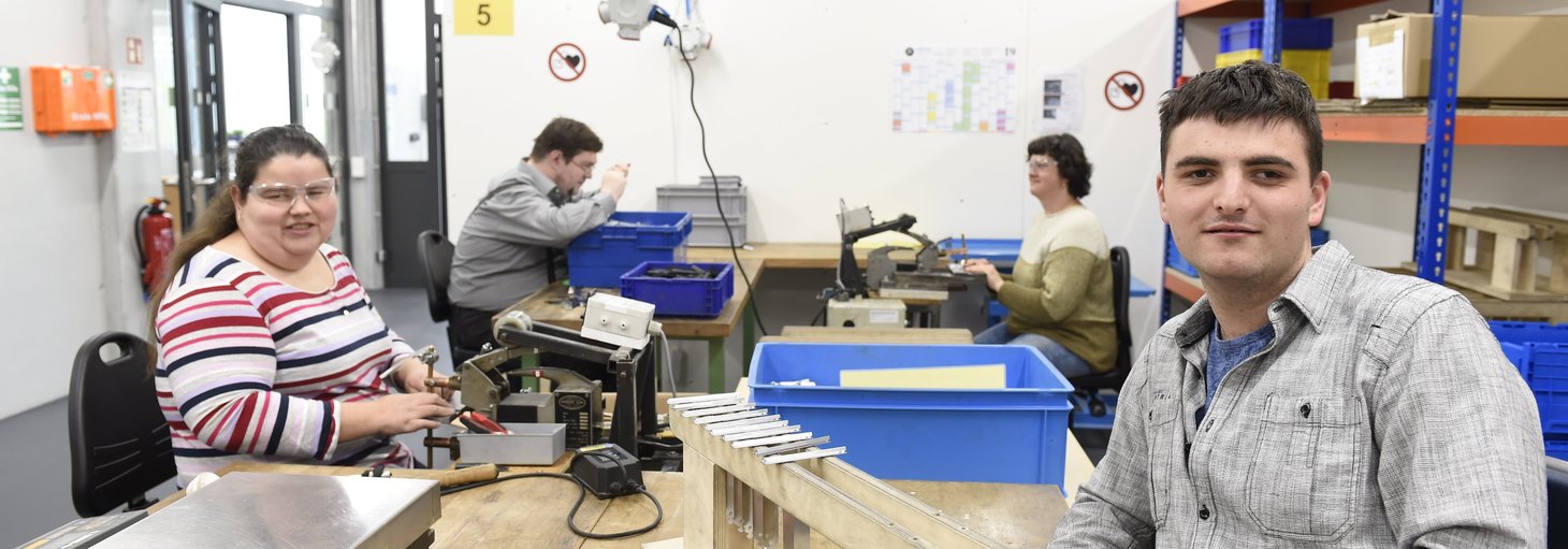 Vier sehbehinderte Menschen bei der Arbeit in einer Werkstatt.