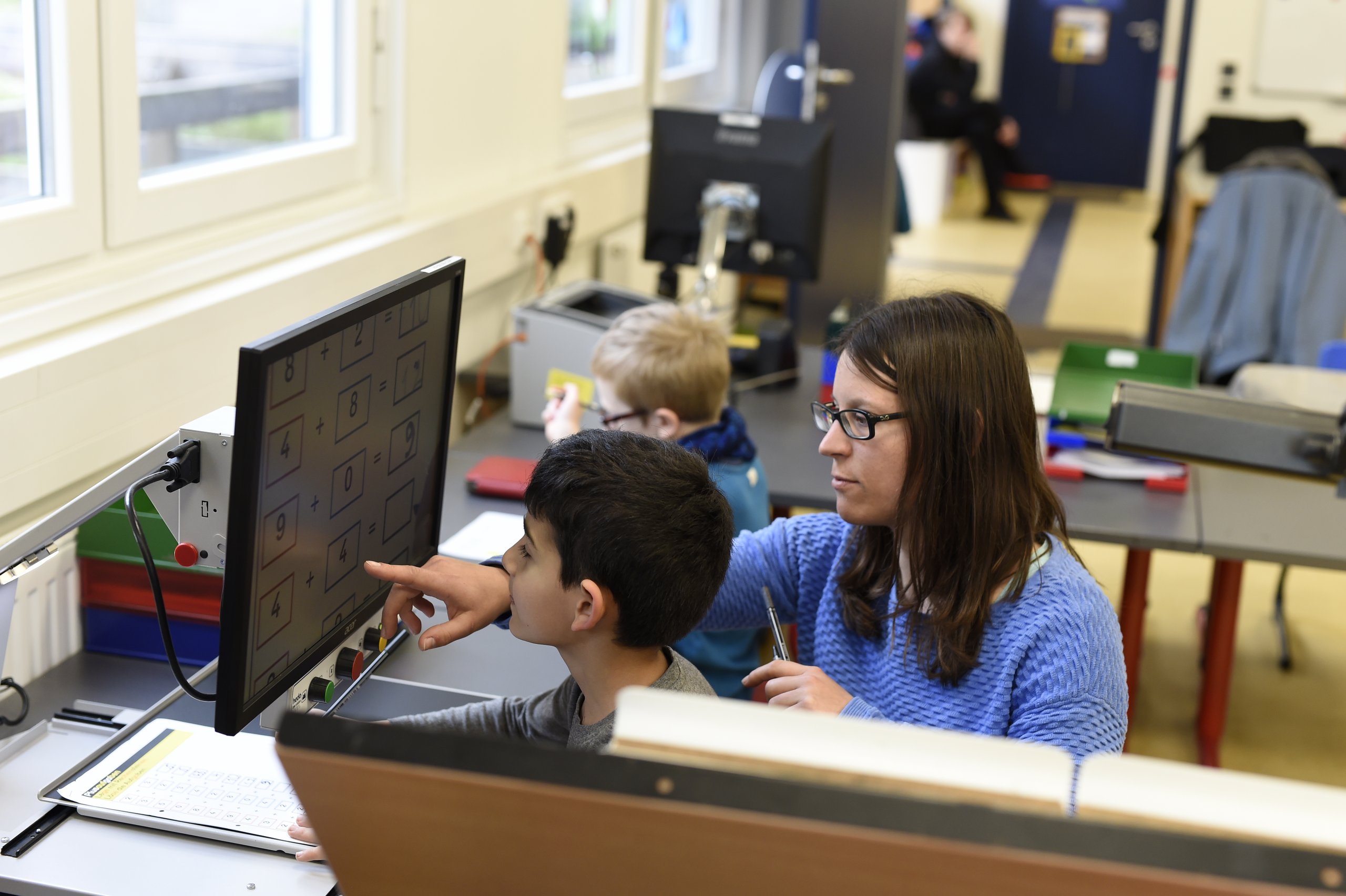 Eine Lehrerin erklärt einem Schüler eine Aufgabe am PC