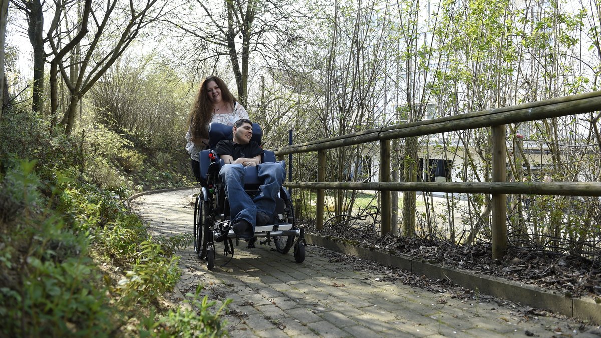 Betreuerin und Bewohner mit Rollstuhl in der Natur
