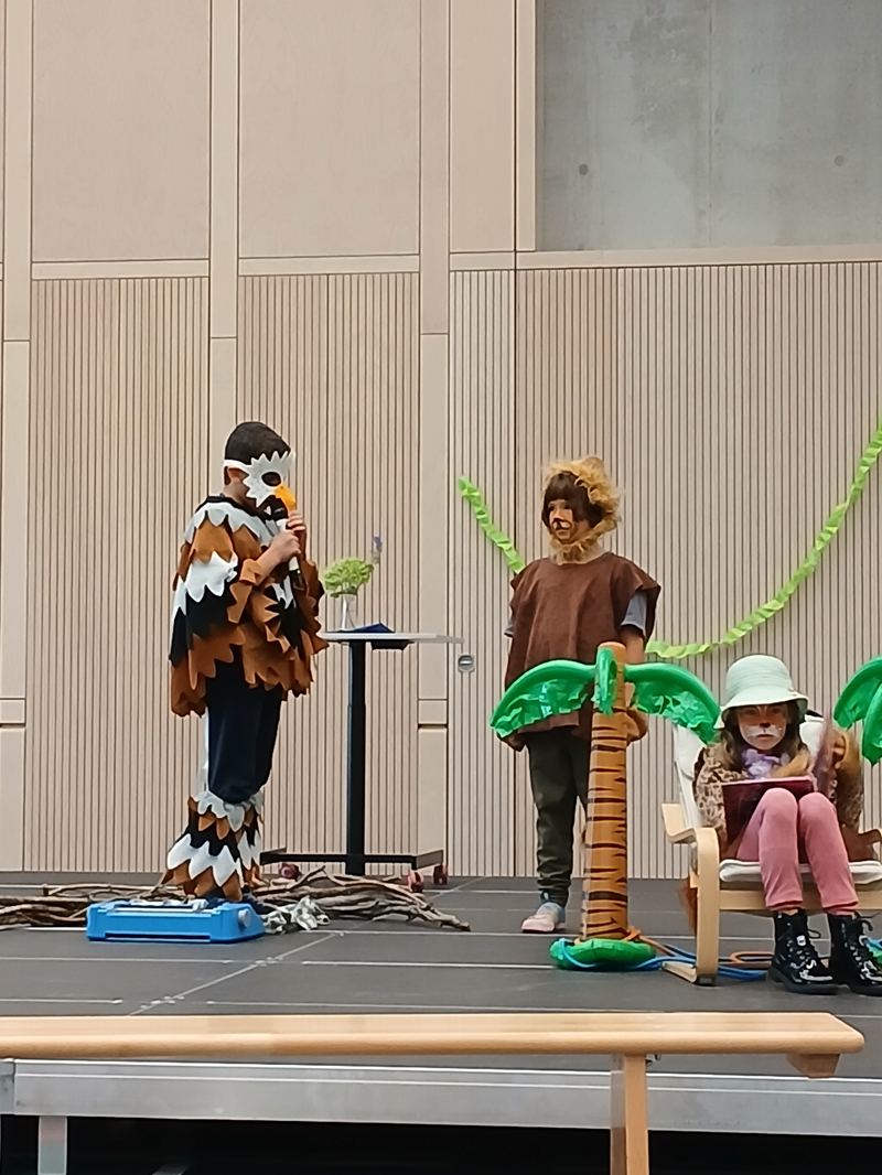 Drei verkleidete Kinder führen ein Theaterstück auf